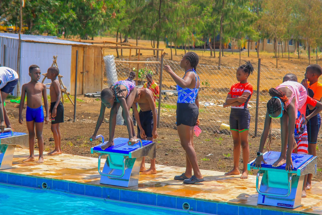 Swimmers lining up at the starting blocks poolside
